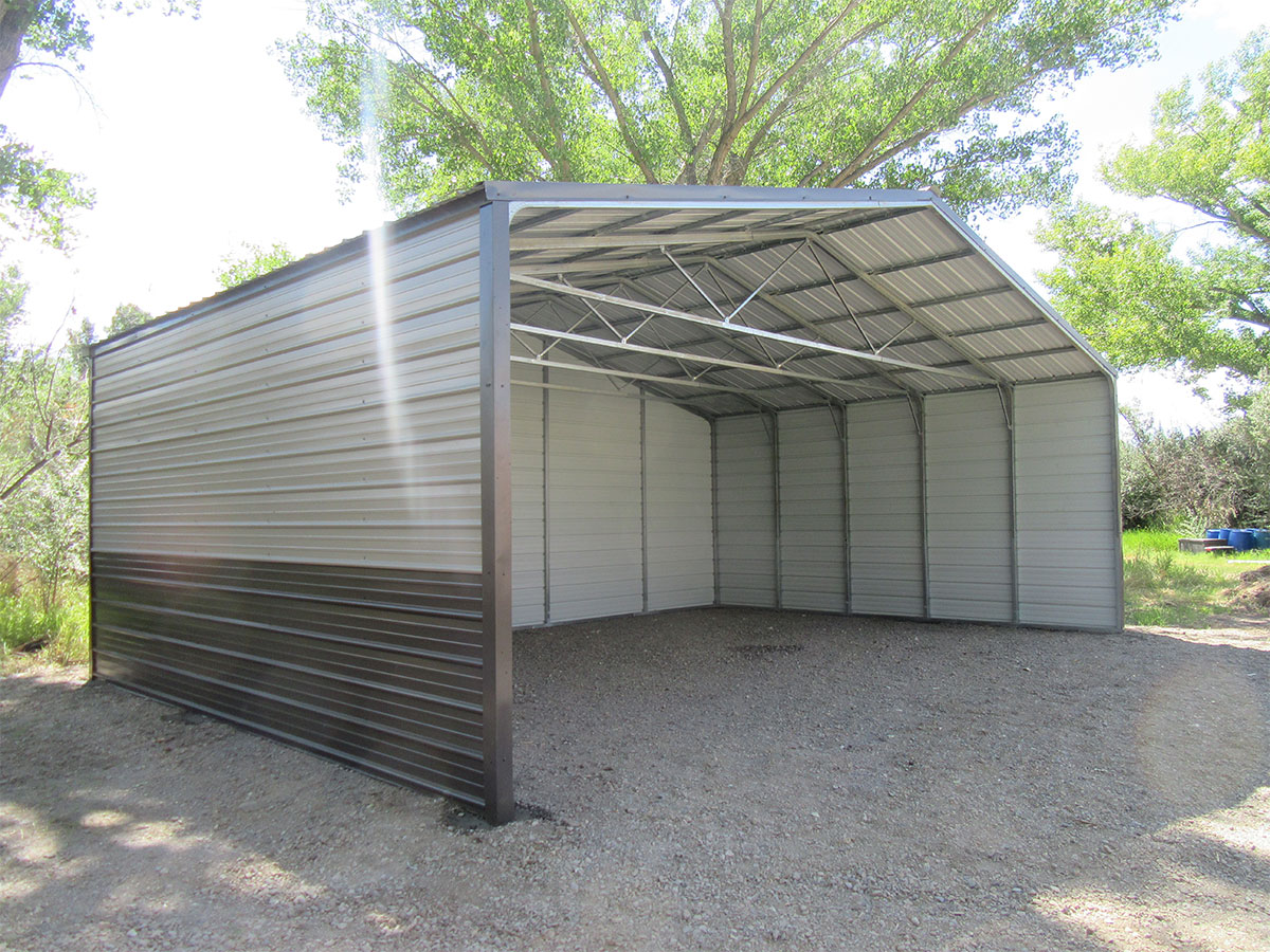 A grand carport structure with a peaked roof, open on three sides, stands elegantly on a gravel surface. It's surrounded by trees and greenery, with sunlight streaming in and casting gentle shadows inside the shelter.
